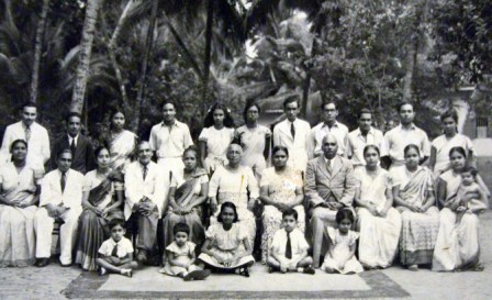 Panadura clan at Dissanyake Walauwa on my Great-grandmothe Annie Dissanayake’s birthday.-She is in the middle in the first row, with my maternal grandmother Eva to her left and my handsome grandfather Romiel Anthony Fernando to her left. My mother Manel, holds Prasanna in her lap on the right first row.  Poddi is 3rd from the left on the back row and Aunty Malini (Honda Amma) behind my mother on the back row, with my father Benny next to her on the back row. My sister Yasoja is seated neatly feet tucked under her on the seated kiddie row and am the grumpy with the feet sticking out, protesting at my bad pudding-bowl haircut. Re-photographed from a original by Chulie de Silva